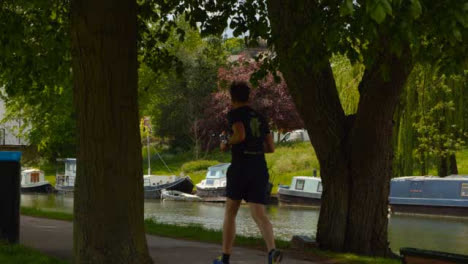 Tracking-Shot-of-Runner-On-Footpath-Next-to-River-Cam