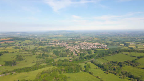 Drone-Shot-Flying-High-Over-Some-Countryside-Fields-Towards-a-Cotswold-Village