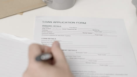 Sliding-Over-the-Shoulder-Shot-of-Person-Filling-In-Loan-Application-Form