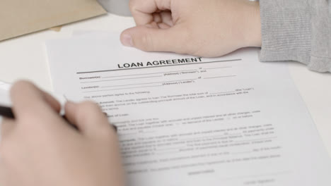 Sliding-Over-the-Shoulder-Shot-of-Person-Filling-In-Loan-Agreement-Form