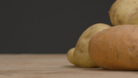Sliding-Shot-of-Assorted-Potatoes-On-Rustic-Wood-Table