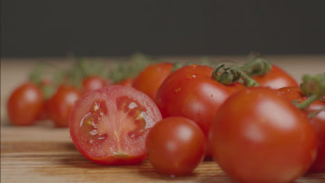 Close-Up-Shot-of-Hand-Placing-Half-a-Tomato-Next-to-Vine-of-Tomatoes