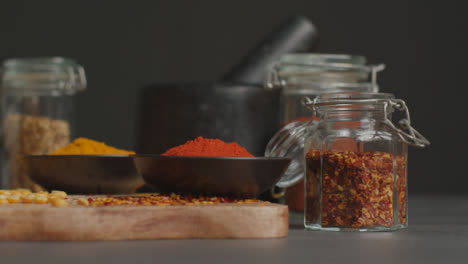 Sliding-Shot-of-Spices-and-Grains-on-Black-Worktop-02