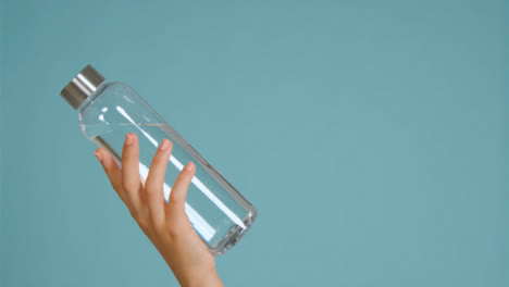 Close-Up-Shot-of-Young-Womans-Hand-Bringing-Water-Bottle-into-Frame-with-Copy-Space-01