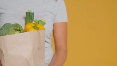 Sliding-Shot-of-Young-Adult-Woman-with-Brown-Paper-Bag-of-Vegetables-with-Copy-Space