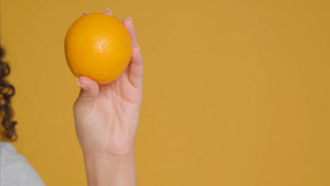 Close-Up-Shot-of-Young-Adult-Woman-Holding-Orange