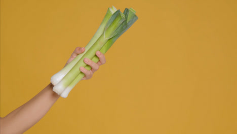 Close-Up-Shot-of-Young-Adult-Woman-Holding-Leeks