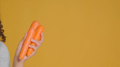 Close-Up-Shot-of-Young-Adult-Woman-Holding-Carrots
