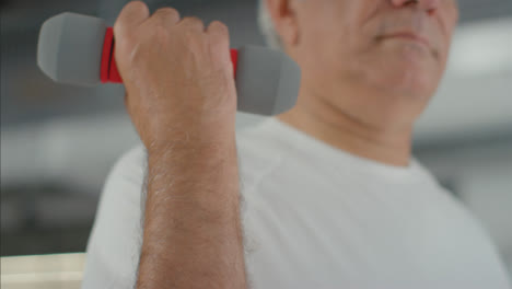 Flachwinkelaufnahme-Eines-älteren-Mannes,-Der-Mit-Kleinen-Gewichten-Im-Fitnessstudio-Trainiert