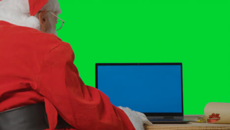 Over-the-Shoulder-Shot-of-Santa-Using-Blue-Screen-Laptop