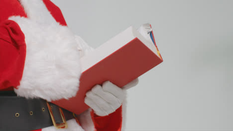 Nahaufnahme-Von-Santas-Händen,-Die-Ein-Großes-Rotes-Buch-Halten