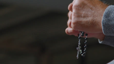 Low-Angle-Shot-of-a-Senior-Mans-Hands-Holding-Rosary-Beads