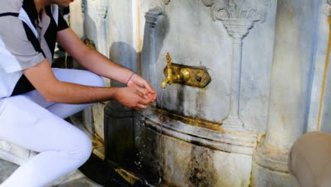 Medium-Shot-of-Young-Man-Washing-Hands-in-Hagia-Sophia-Fountain