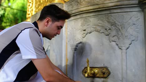 Medium-Shot-of-Young-Man-Washing-Hands-in-a-Hagia-Sophia-Fountain