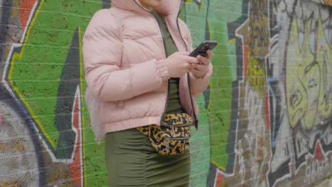 Mid-Section-of-Woman-Waiting-On-Urban-Street-with-Mobile-Phone