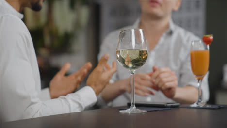 Close-Up-Shot-of-Glass-of-Wine-On-Table-as-Men-Talk-In-Background