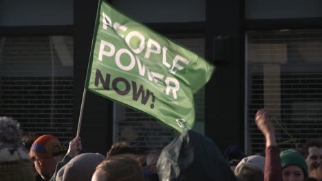 Handheld-Shot-of-'People-Power-Now'-Flag-Flying-During-Climate-Change-Protests-In-Glasgow
