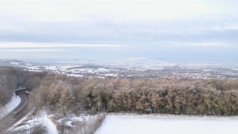 Drone-Shot-Flying-Over-Snowy-Fields-and-Trees-Toward-Cotswold-Village-Part-1-of-4