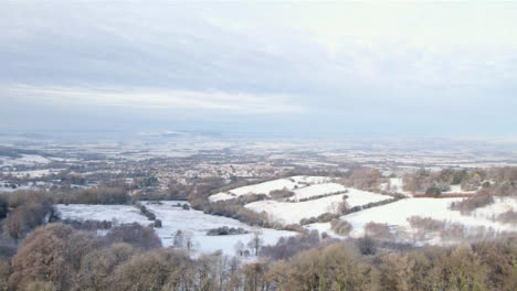 Drone-Shot-Flying-Over-Snow-Covered-Fields-and-Trees-Toward-Cotswold-Village-Part-1-of-2