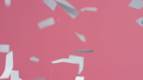 Stationary-Shot-of-Silver-Confetti-Falling-Against-Pink-Background