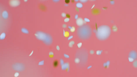 Stationary-Shot-of-Blue-and-Gold-Confetti-Falling-Against-Pink-Background