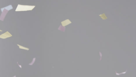 Stationary-Shot-of-Coloured-Strip-Confetti-Falling-Against-a-Grey-Background