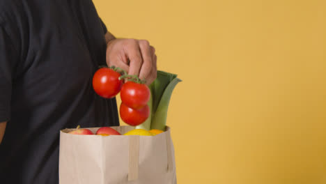 Close-Up-Side-Shot-of-Man-Putting-Tomatoes-Into-Bag-