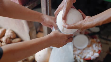 High-Angle-Shot-of-Hands-Pouring-Coconut-Water-into-a-Bag