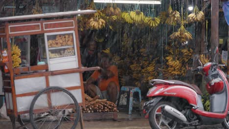 Long-Shot-of-People-Sitting-at-Banana-Stand-In-the-Rain
