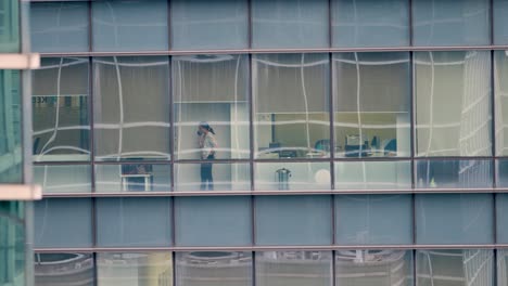 Long-Shot-of-Woman-Talking-On-Phone-at-Skyscraper-Window