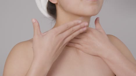 Mid-Shot-of-a-Young-Woman-Blending-Cream-into-Her-Neck