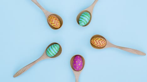 Top-Down-Shot-of-Rotating-Easter-Eggs-In-Wooden-Spoons