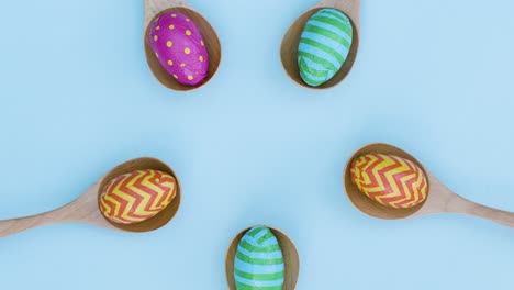 Ascending-Top-Down-Shot-of-Rotating-Easter-Eggs-In-Wooden-Spoons