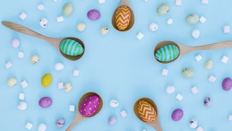 Top-Down-Shot-of-Rotating-Easter-Eggs-In-Wooden-Spoons-with-Confectionary