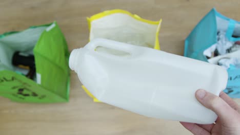 Top-Down-Pull-Focus-Shot-of-a-Person-Throwing-Plastic-Carton-into-Recycling-Bag