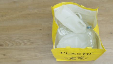Top-Down-Shot-of-a-Person-Throwing-Plastic-Carton-into-Recycling-Bag-with-Copy-Space