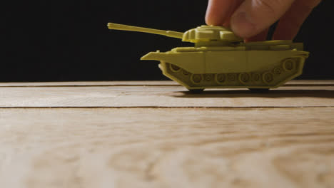 Close-Up-Shot-of-Toy-Tank-Rolling-Through-Frame