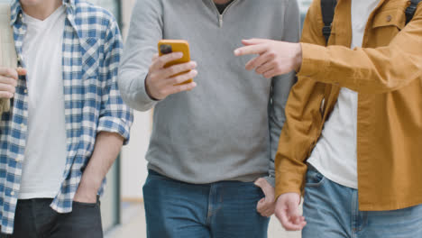 Tracking-Shot-of-Students-Walking-and-Laughing-at-Content-On-Smartphone