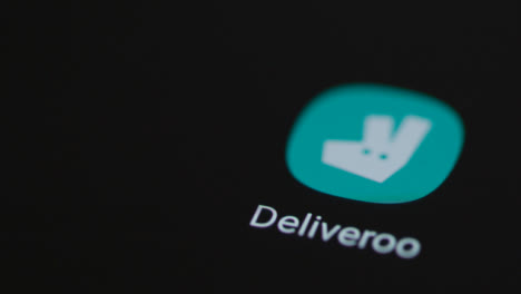 Close-Up-Shot-of-Finger-Tapping-the-Deliveroo-App-On-Smartphone-Screen