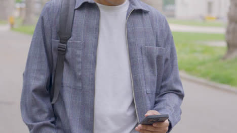 Tracking-Shot-of-Young-Man-Walking-Whilst-Looking-at-Smartphone