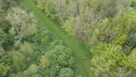 Drone-Aerial-Shot-Of-Man-On-Mountain-Bike-Cycling-Along-Trail-Through-Countryside-And-Woodland-3