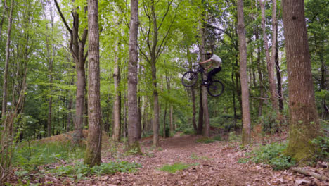 Slow-Motion-Shot-Of-Man-On-Mountain-Bike-Making-Mid-Air-Jump-On-Dirt-Trail-Through-Woodland