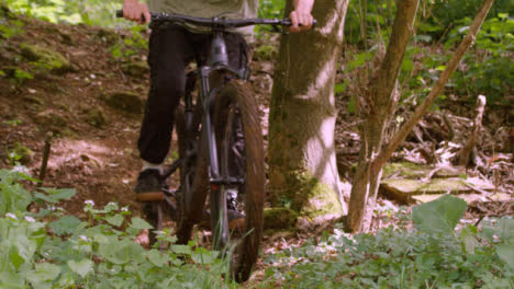 Close-Up-Slow-Motion-Shot-Of-Man-On-Mountain-Bike-Cycling-Along-Trail-Through-Woodland
