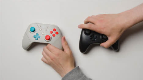 Overhead-Studio-Shot-Of-Hands-Reaching-In-To-Pick-Up-Video-Game-Controllers