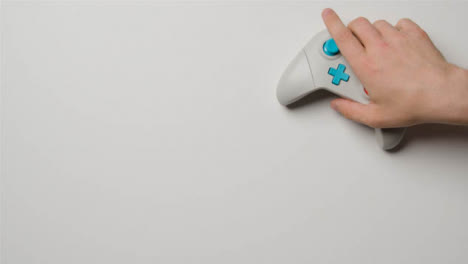Overhead-Studio-Shot-Of-Hand-Reaching-In-To-Pick-Up-Video-Game-Controller-4