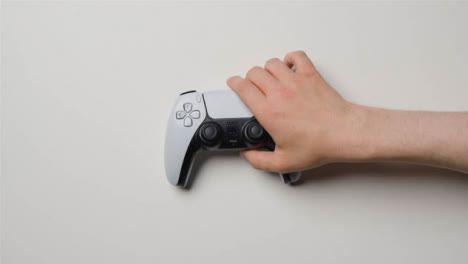 Overhead-Hand-Reaching-Picking-Up-Sony-PlayStation-Video-Game-Controller-1
