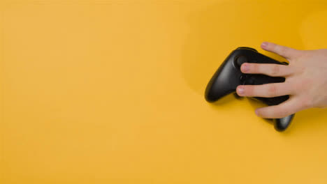 Overhead-Studio-Shot-Of-Hand-Reaching-In-To-Pick-Up-Video-Game-Controller-7