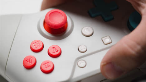 Close-Up-Of-Hand-Picking-Up-One-Of-Two-Video-Game-Controllers-White-Background