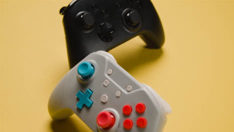 Studio-Close-Up-Of-Two-Video-Game-Controllers-On-Yellow-Background