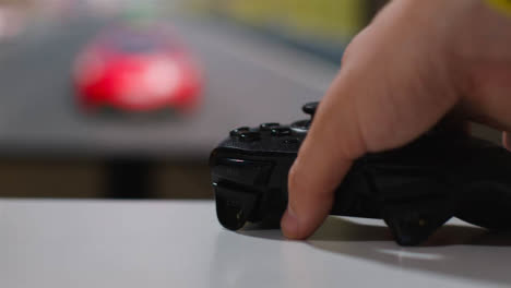 Close-Up-Hand-Picking-Up-Video-Game-Controller-Driving-Game-Screen-Background-2